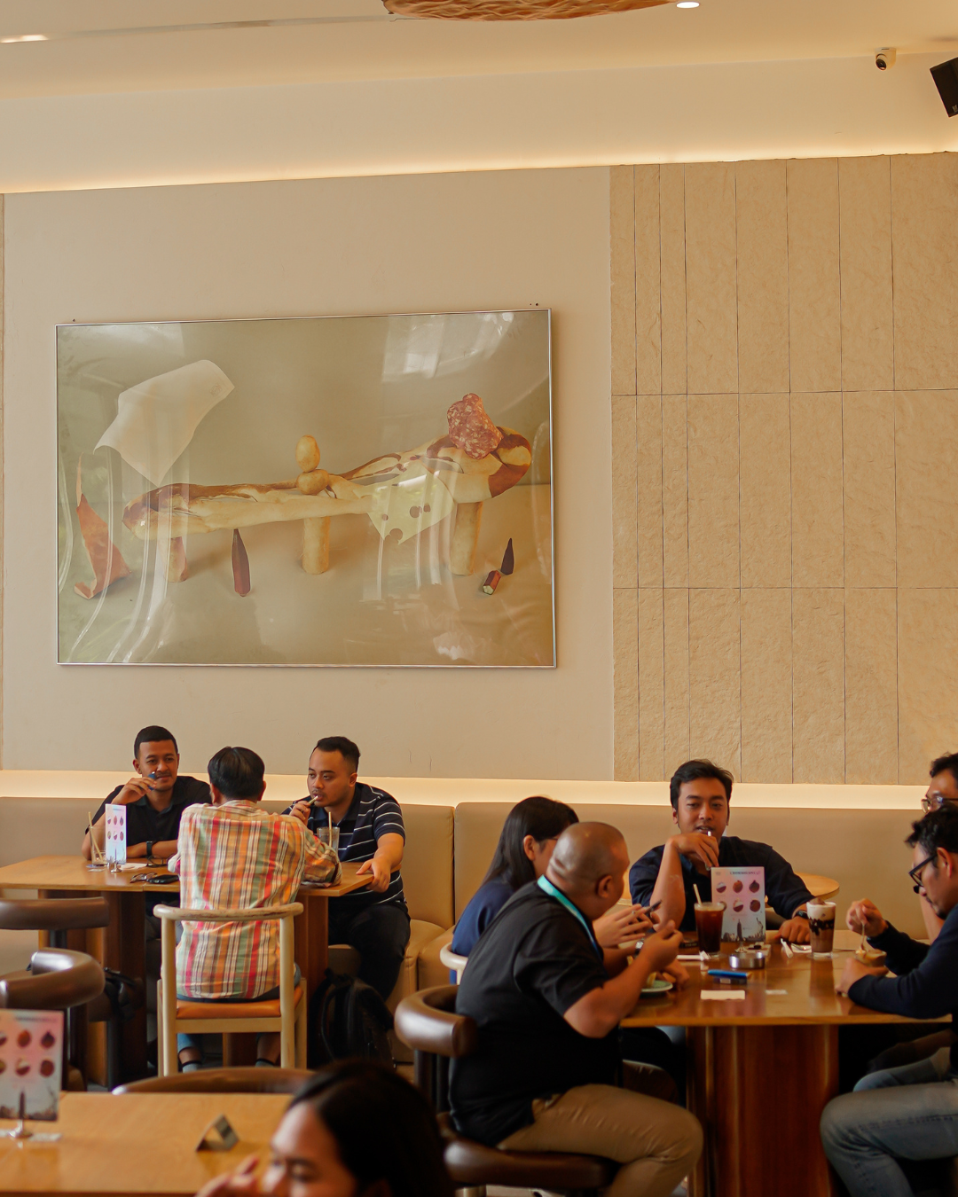 Customers seated inside Bakerman, a popular brunch spot and pastry shop in Jakarta, enjoying coffee and pastries in a cozy, sunlit cafe setting